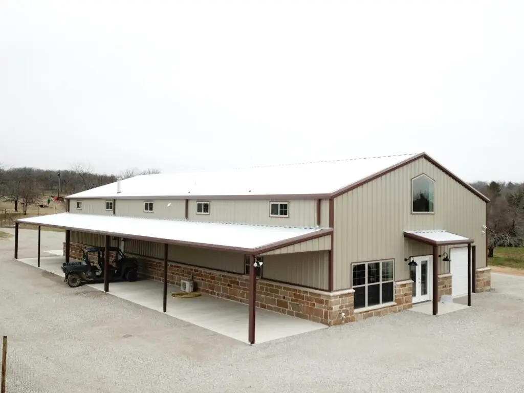 tan barndominium with white roof and brown gutters