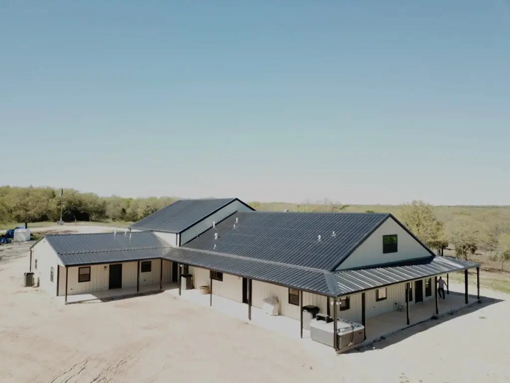 white and gray barndominium with wrap around porch