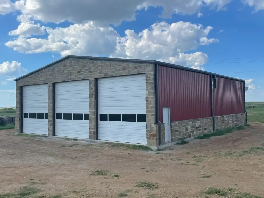 red and rock barndo with 3 white garage doors