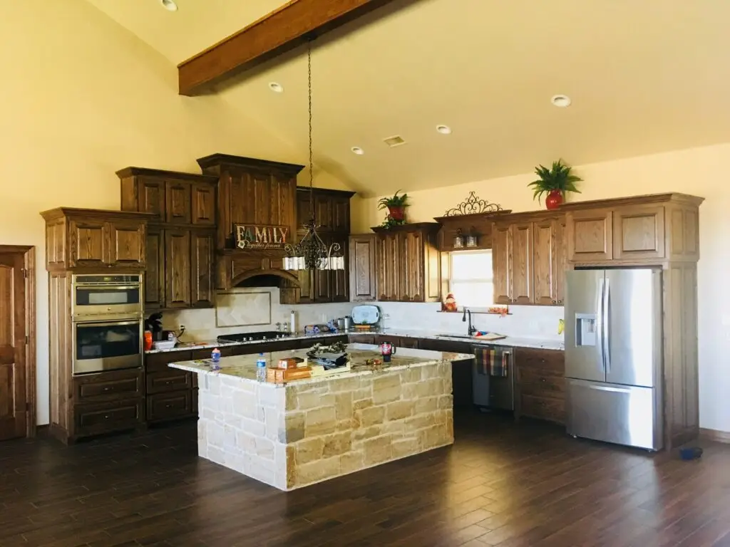 view of a kitchen with dark brown cabinets and a light stone island
