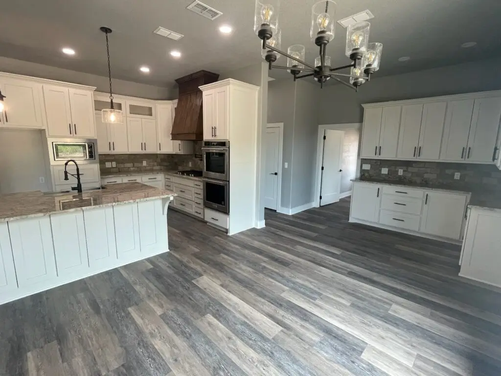kitchen with dark gray wood floors, white cabinets and chandeliers
