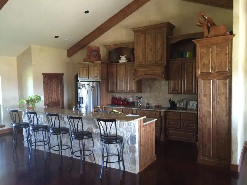 view of a older style kitchen with brown cabinets and espresso colored flooring.