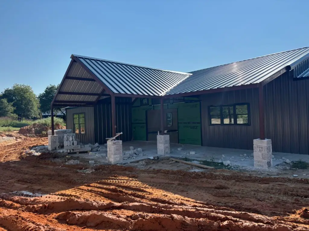 Dark brown and black barndominium with cream stone accent pillars