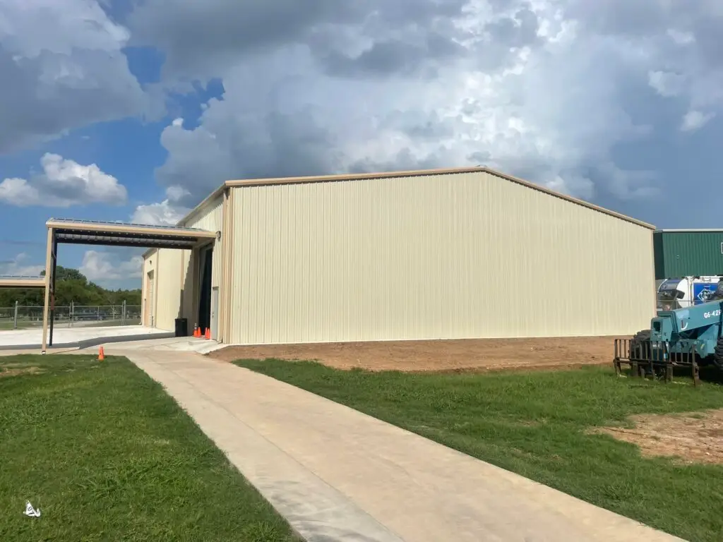 light tan barndominium, view is from the side and there is a small porch