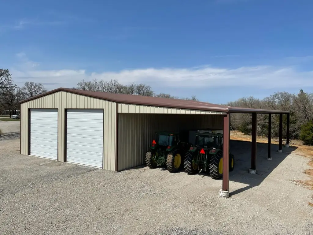 tan shop metal building with dark brown roof and two white garage doors